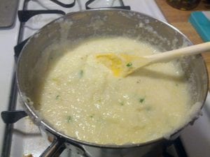 Adding cheese to grits in a saucepan