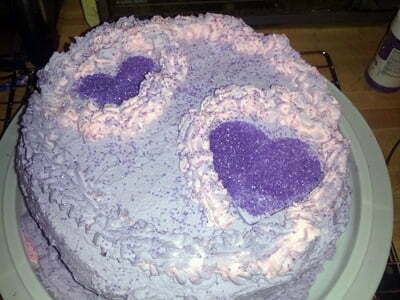 The cake is decorated with frosting and a purple flower.