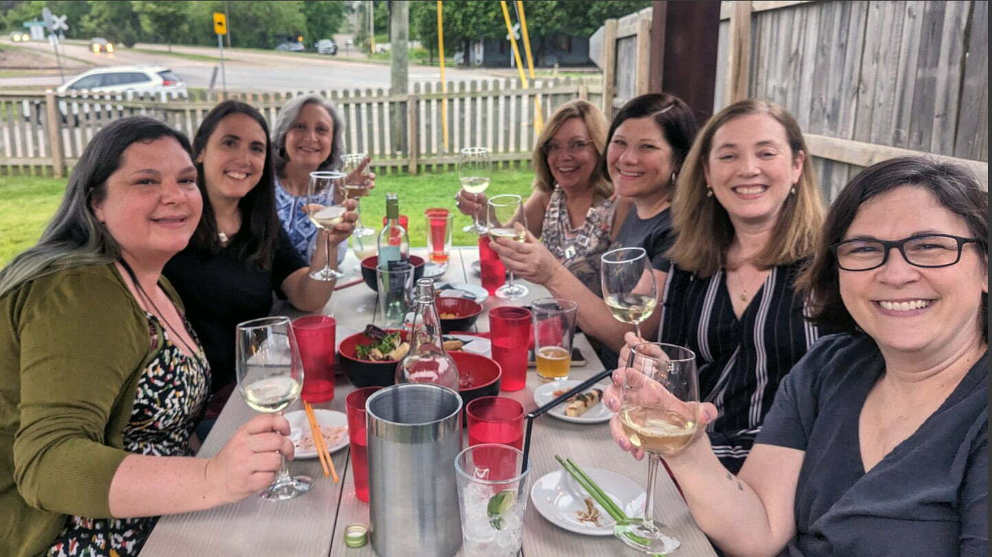 A group is seated at a table with wine glasses.